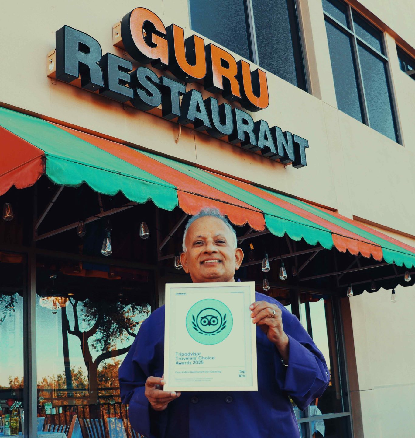 Uday Kadam holding an award from Tripadvisor for being in the top 10% worldwide